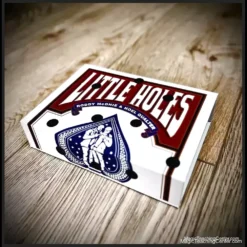 Still from Little Holes magic trick video, showing a red Bicycle card box with four dark, seemingly impossible holes that have transformed from drawn dots, by Roddy McGhie and Noel Qualter.