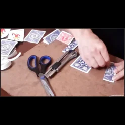 Hands demonstrating the fabrication of a custom trick card, illustrating the Magia Estudio video course for learning DIY gimmick card secrets, available as an instant download.